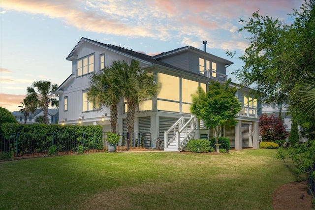 back of house with stairway, fence, and a yard