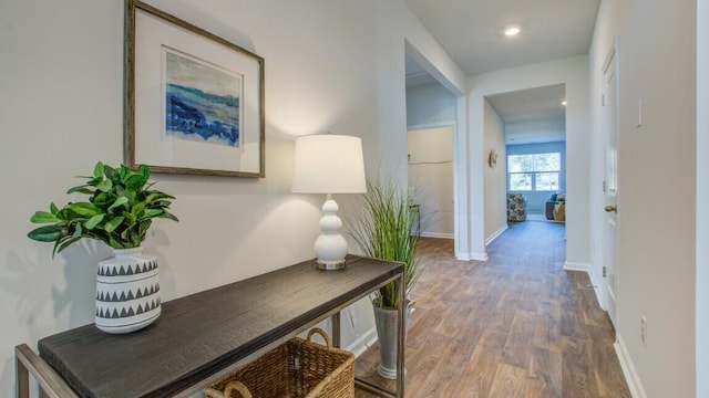 corridor featuring wood finished floors, baseboards, and recessed lighting