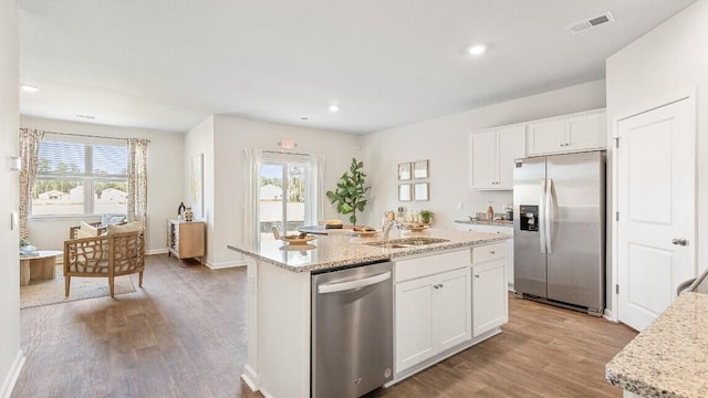 kitchen with appliances with stainless steel finishes, light wood-style flooring, healthy amount of natural light, white cabinets, and recessed lighting