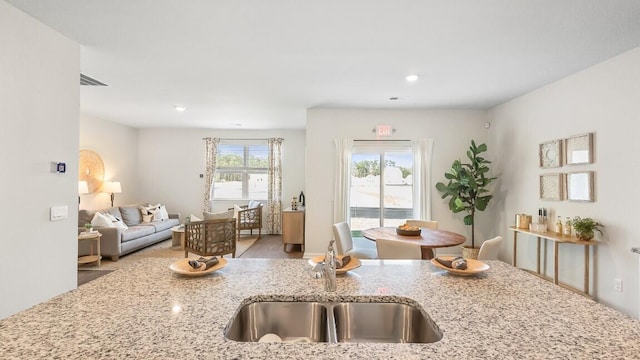 kitchen featuring a sink, open floor plan, light stone countertops, and recessed lighting
