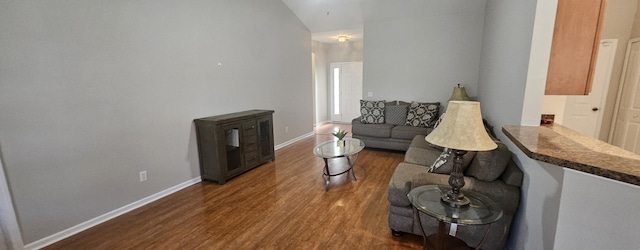 living area with lofted ceiling, wood finished floors, and baseboards