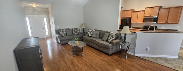 living area with a towering ceiling, baseboards, and wood finished floors