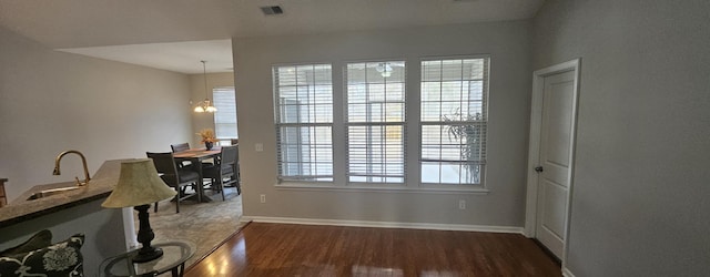 unfurnished dining area with a wealth of natural light, visible vents, dark wood-type flooring, and a sink