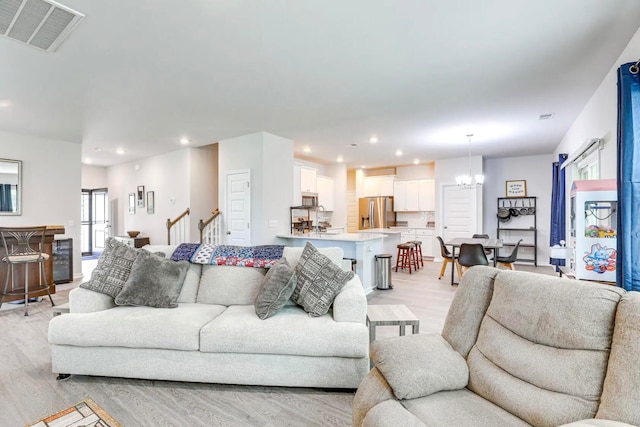 living room with light wood-type flooring and an inviting chandelier