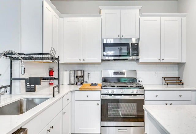 kitchen with white cabinets, appliances with stainless steel finishes, and tasteful backsplash