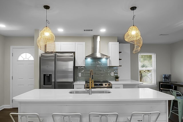 kitchen with visible vents, white cabinets, stainless steel fridge with ice dispenser, wall chimney exhaust hood, and a kitchen bar