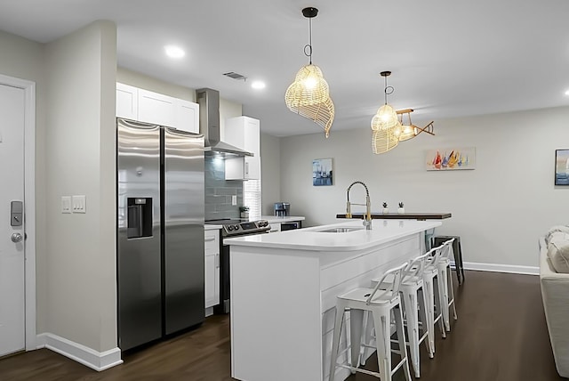 kitchen with stainless steel appliances, a sink, visible vents, wall chimney range hood, and dark wood-style floors