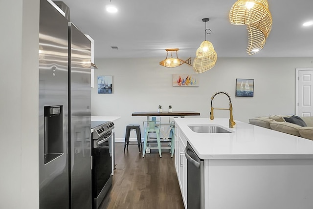 kitchen with white cabinets, dark wood-type flooring, stainless steel appliances, light countertops, and a sink