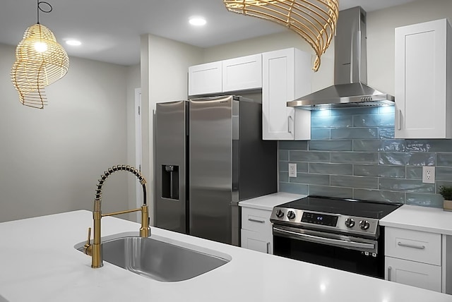 kitchen with white cabinets, decorative backsplash, wall chimney exhaust hood, appliances with stainless steel finishes, and a sink