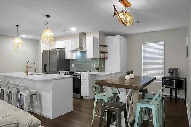 kitchen with dark wood finished floors, backsplash, appliances with stainless steel finishes, a sink, and wall chimney exhaust hood