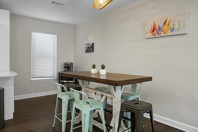 dining space featuring dark wood-style floors, visible vents, and baseboards