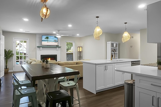 kitchen with a wealth of natural light, light countertops, a sink, and a lit fireplace