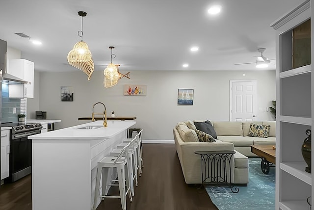 kitchen featuring visible vents, electric stove, dark wood-type flooring, light countertops, and a sink