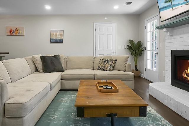 living area featuring recessed lighting, a brick fireplace, and visible vents