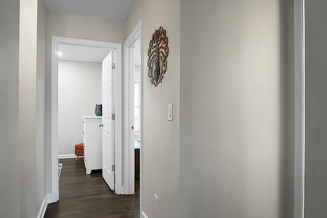 hallway featuring baseboards and dark wood finished floors