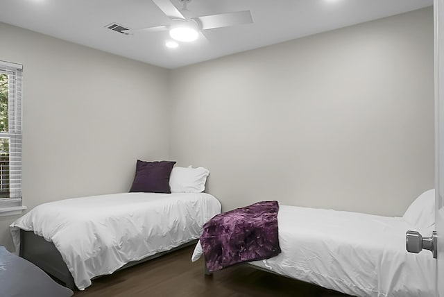 bedroom featuring a ceiling fan, visible vents, and wood finished floors