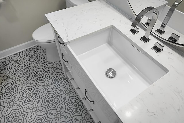 bathroom with baseboards, vanity, toilet, and tile patterned floors