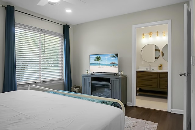 bedroom featuring ensuite bathroom, ceiling fan, dark wood-type flooring, a sink, and baseboards