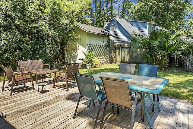 wooden deck with an outbuilding, a yard, outdoor dining area, and fence