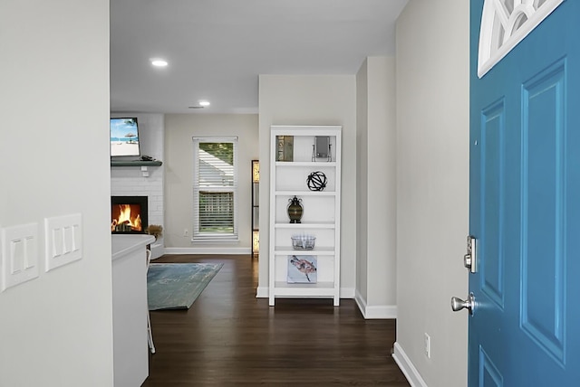 foyer with recessed lighting, a fireplace, dark wood finished floors, and baseboards