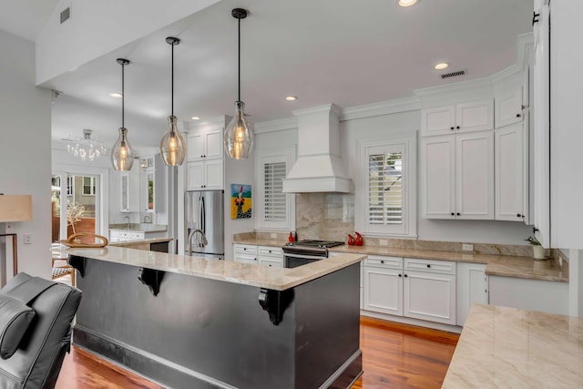 371 Live Palmetto Blf, Mount Pleasant, SC 29464 - kitchen featuring appliances with stainless steel finishes, custom range hood, decorative light fixtures, a breakfast bar area, and an island with sink