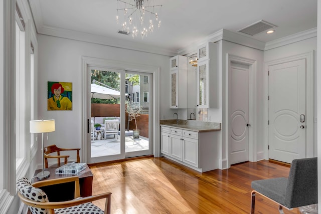 371 Live Palmetto Blf, Mount Pleasant, SC 29464 - doorway with sink, an inviting chandelier, ornamental molding, and light wood-type flooring