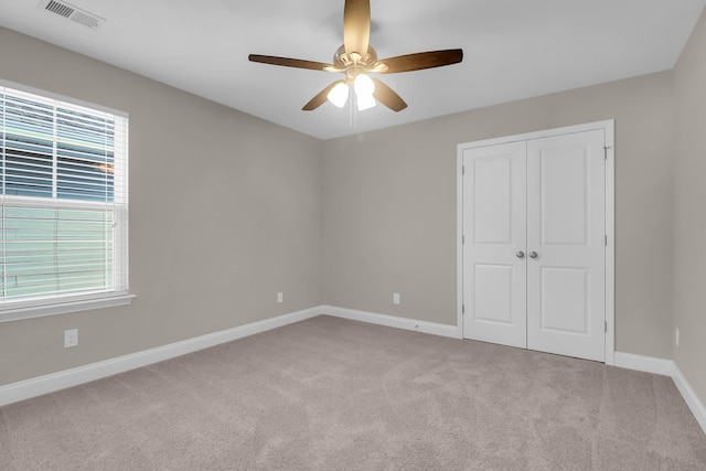 unfurnished bedroom with light carpet, multiple windows, and ceiling fan