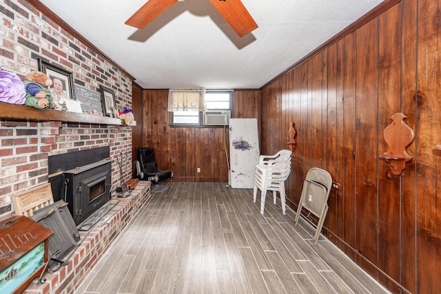 unfurnished living room with hardwood / wood-style flooring, crown molding, a brick fireplace, and ceiling fan