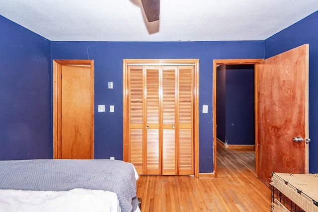 bedroom with ceiling fan, a closet, and light hardwood / wood-style flooring