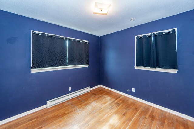 spare room with a baseboard radiator and wood-type flooring