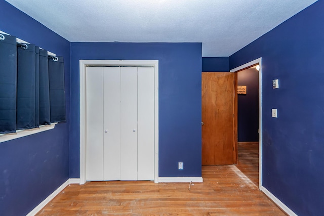 unfurnished bedroom with light hardwood / wood-style flooring, a closet, and a textured ceiling