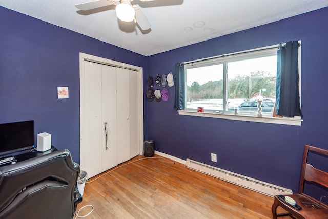 office featuring ceiling fan, a baseboard heating unit, and light wood-type flooring