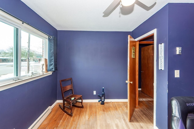 living area featuring wood-type flooring, ceiling fan, and a baseboard radiator