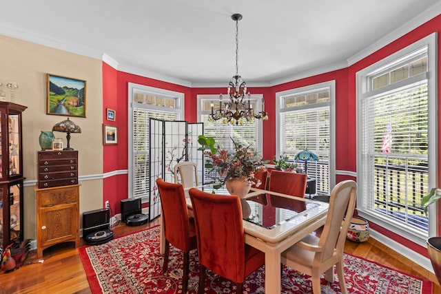 dining space featuring a chandelier, crown molding, and wood finished floors