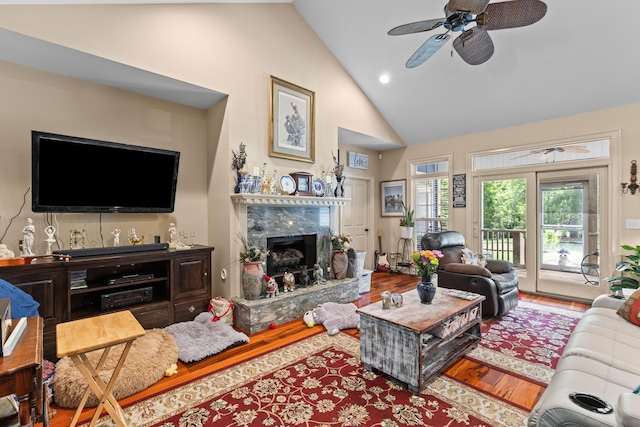 living room featuring high vaulted ceiling, wood finished floors, a ceiling fan, a high end fireplace, and recessed lighting