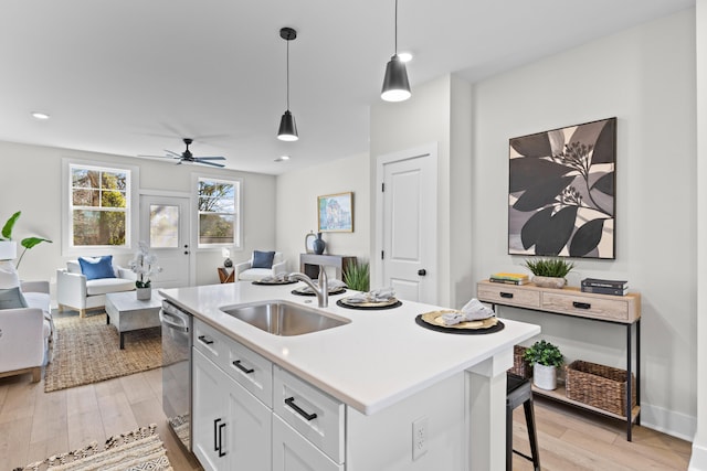 kitchen with white cabinets, a kitchen island with sink, open floor plan, and a sink