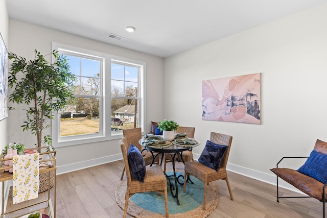 dining room with light wood-style flooring, visible vents, and baseboards