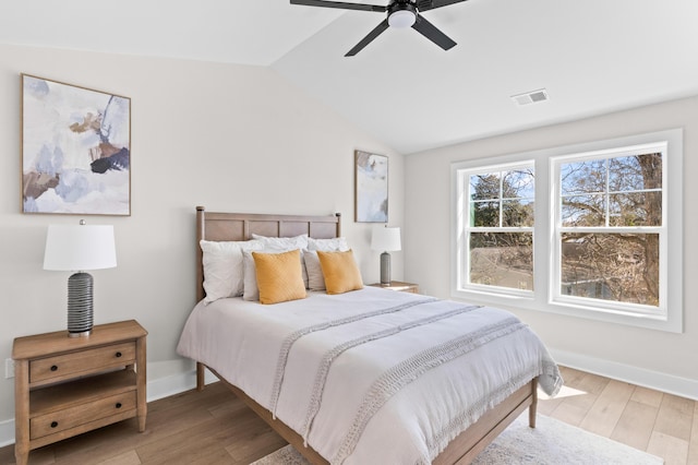 bedroom with lofted ceiling, light wood-style floors, visible vents, and baseboards