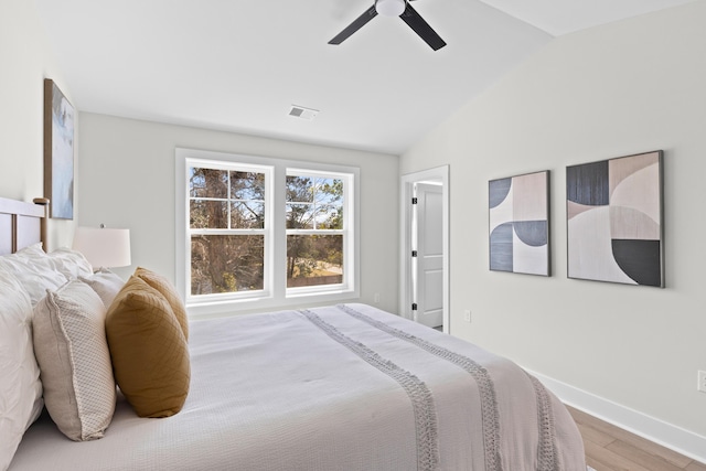 bedroom featuring visible vents, ceiling fan, vaulted ceiling, wood finished floors, and baseboards