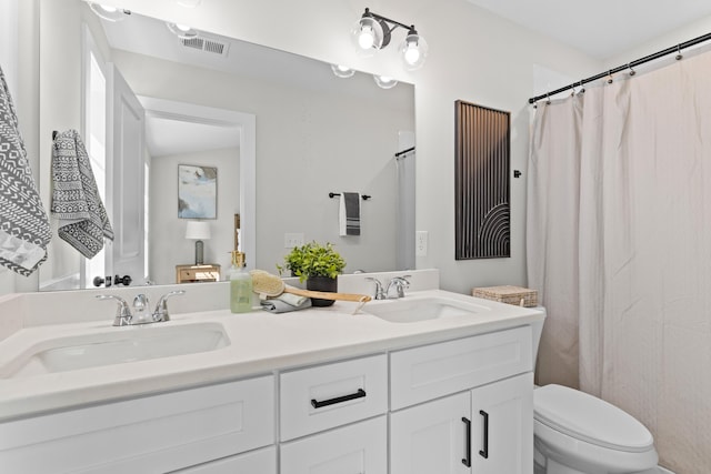 full bath with visible vents, a sink, toilet, and double vanity