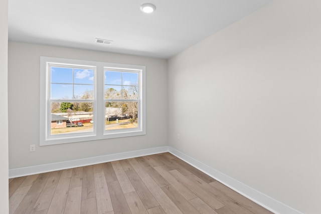 unfurnished room featuring light wood-style floors, visible vents, and baseboards