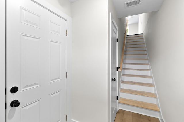 stairs with wood finished floors, visible vents, and baseboards