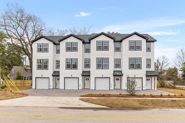 townhome / multi-family property featuring a garage, roof with shingles, and board and batten siding