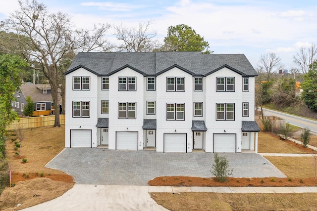 view of property featuring a garage, driveway, and a shingled roof