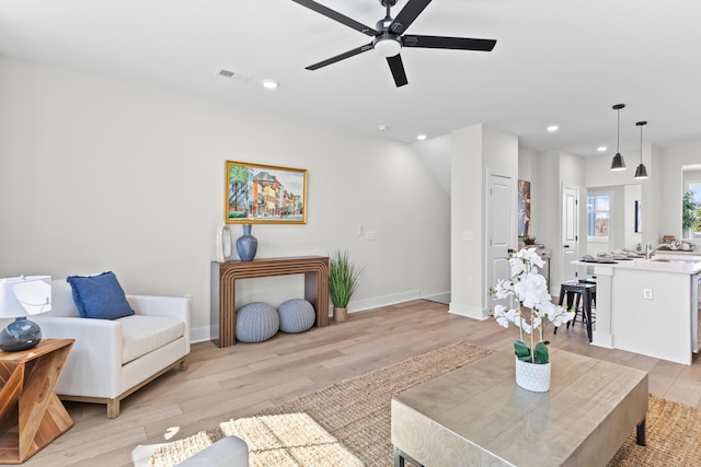 living room featuring baseboards, light wood finished floors, visible vents, and recessed lighting