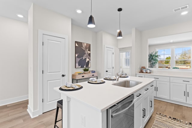 kitchen with a sink, visible vents, light countertops, stainless steel dishwasher, and a center island with sink