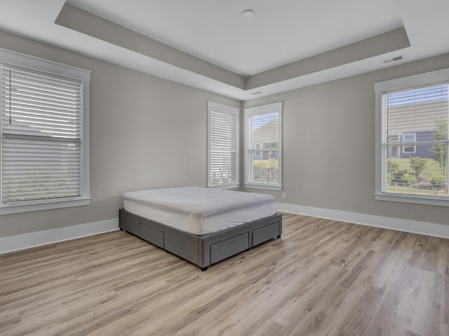 253 River Martin Ct, Summerville, SC 29483 - bedroom featuring light wood-type flooring, a tray ceiling, baseboards, and visible vents