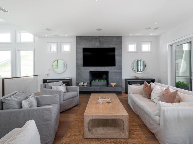 living area with a large fireplace, wood finished floors, and visible vents