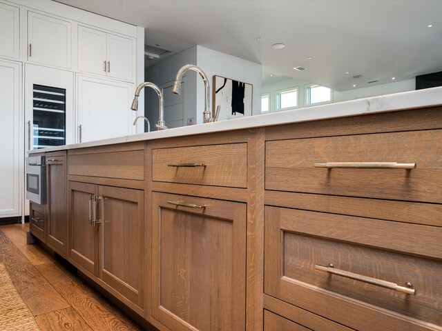 kitchen featuring visible vents, wine cooler, wood finished floors, light countertops, and white cabinets
