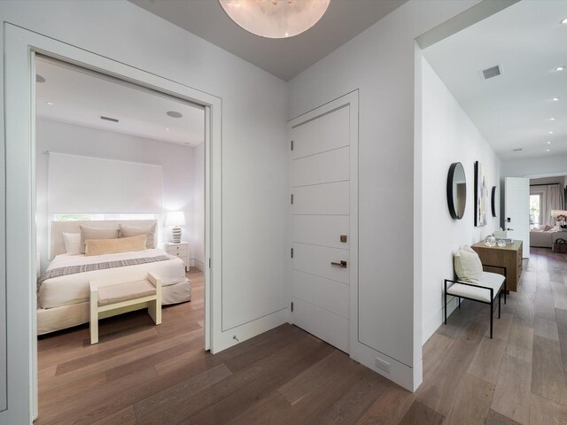 hallway with visible vents, recessed lighting, baseboards, and wood finished floors